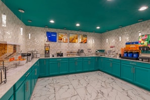 Cozinha moderna com armários verde-água, piso de mármore e espaço para café.