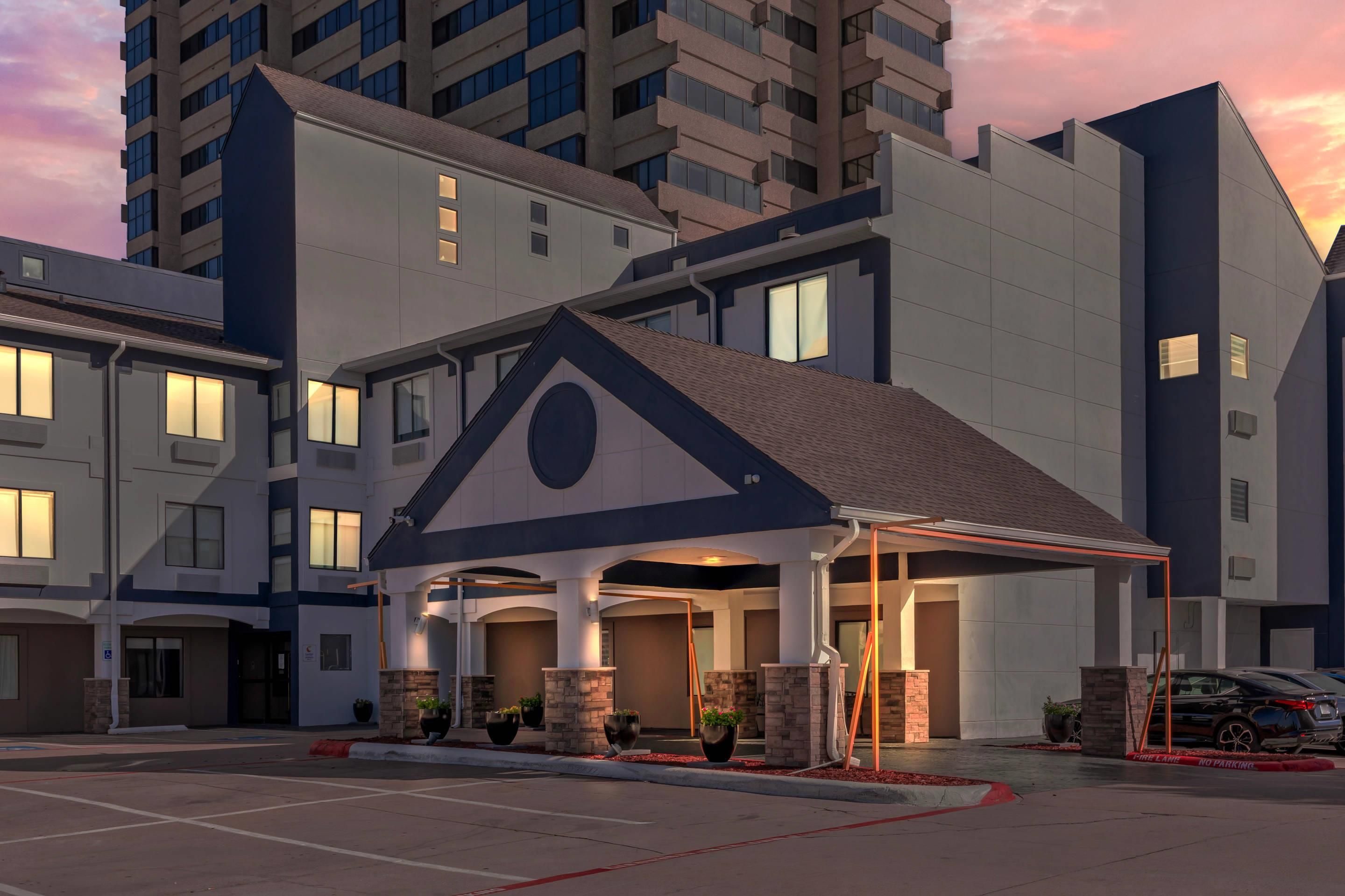 Ein Hotel mit modernem Design, das einen markanten Eingangsbereich mit einem dreieckigen Dach und einer überdachten Wartezone bietet.