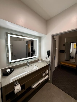 Un bagno moderno con uno specchio grande, un lavabo e una panca.