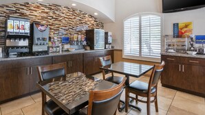 A modern kitchen with a coffee station, dining area, and a TV mounted on the wall. - Best Western Tolleson Hotel (Tolleson)