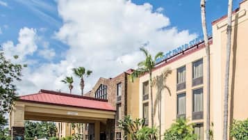 Ein Hotel mit rotem Dach, einer überdachten Eingangsparte und Palmen.