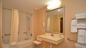 Un baño con bañera, lavamanos, espejo y toallero.
