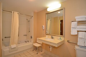 Ein Badezimmer mit einer Badewanne, einem Waschbecken, einem Spiegel und einem Handtuchhalter.