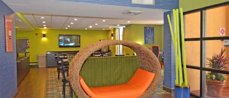 A room with a circular hanging chair, a television, and a reception desk.