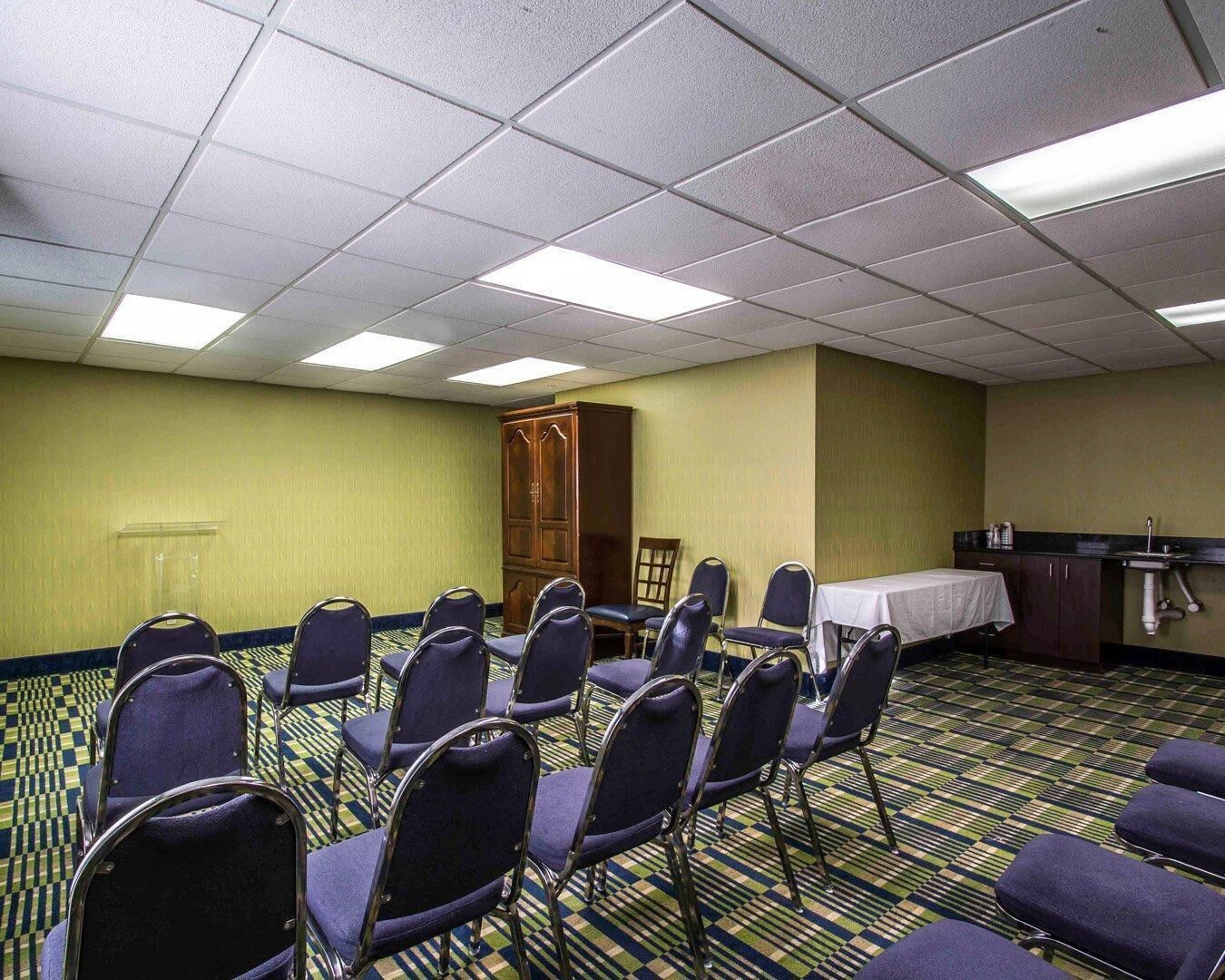 A conference room with rows of chairs, a table, and a cabinet.