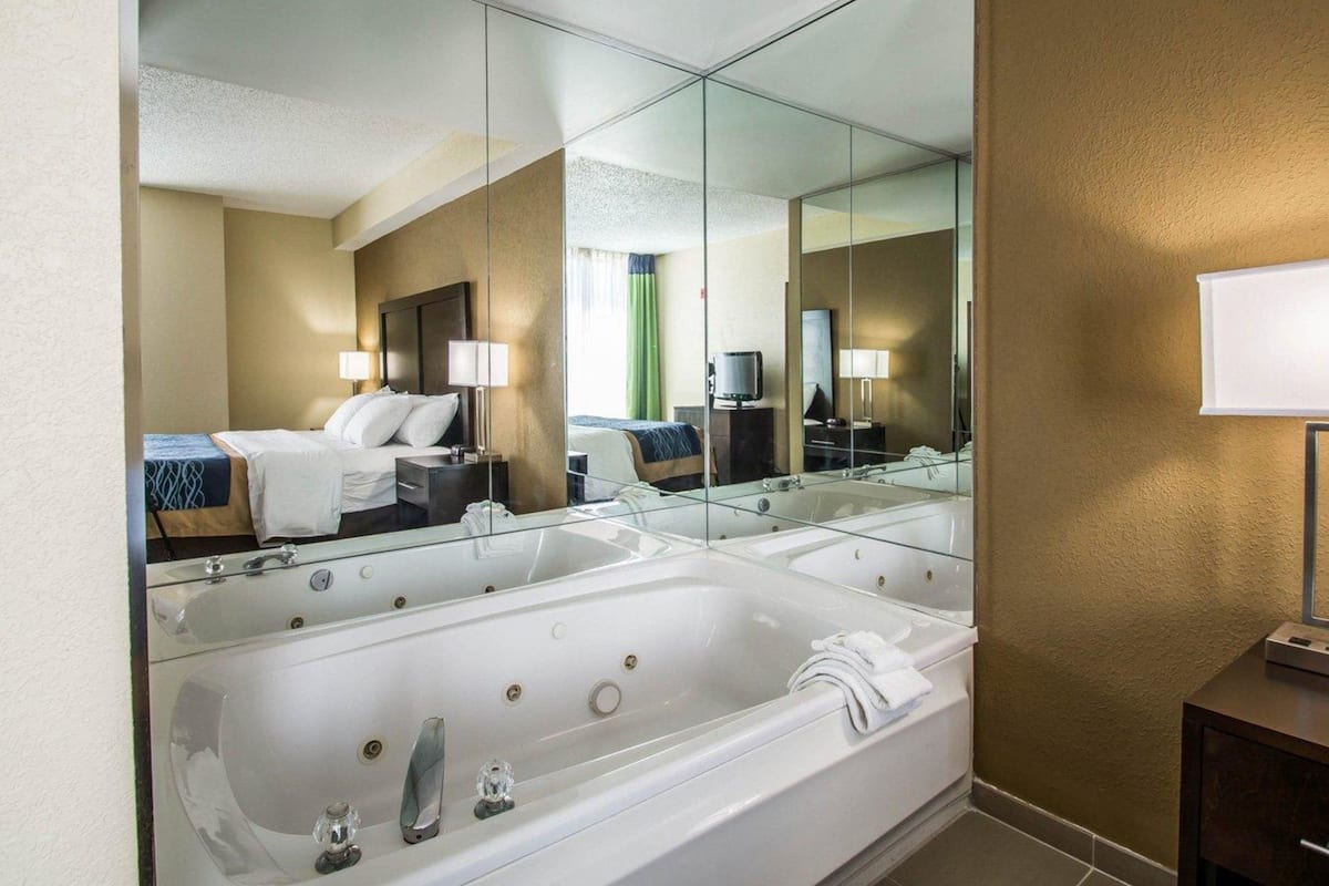 Un baño de hotel con un espejo grande, una bañera, un lavamanos y un tocador con espejo.