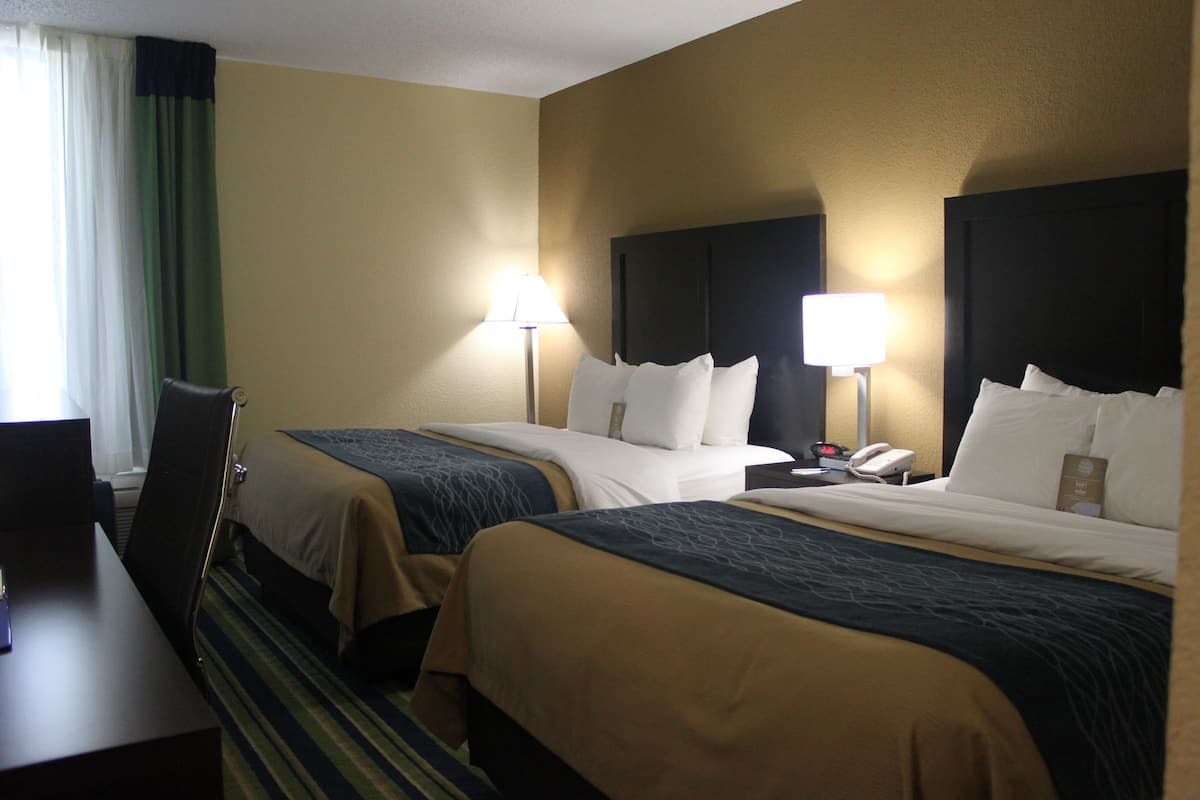 Habitación de hotel con dos camas, un escritorio y una silla.