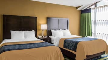 A hotel room with two beds, a nightstand with a lamp, and a view of the outside through a window with curtains.