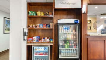 Un quiosco de autoservicio con una sección refrigerada y un congelador, lleno de aperitivos y bebidas.
