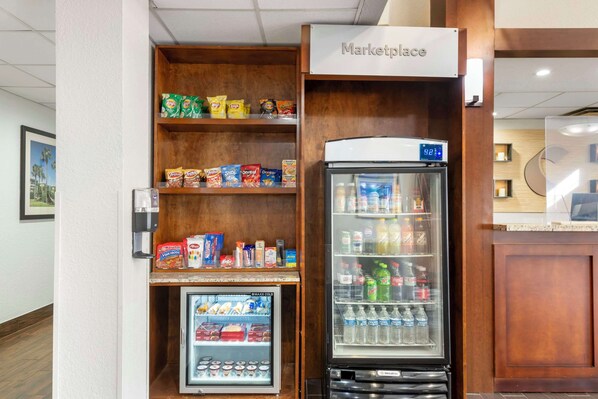 A self-service kiosk with a refrigerated section and a freezer, stocked with snacks and beverages. - Comfort Suites Downtown (Orlando)