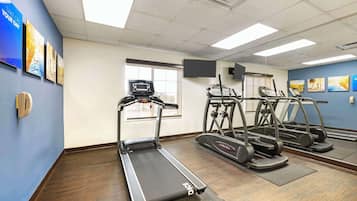 A fitness room with treadmills, a stationary bike, and a wall-mounted TV.