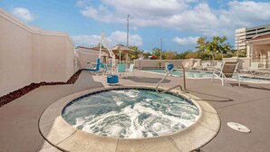 Uma área de piscina com hidromassagem, espreguiçadeiras e um espaço de estar coberto.