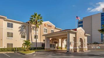 A hotel with a covered entrance, palm trees, and an American flag.