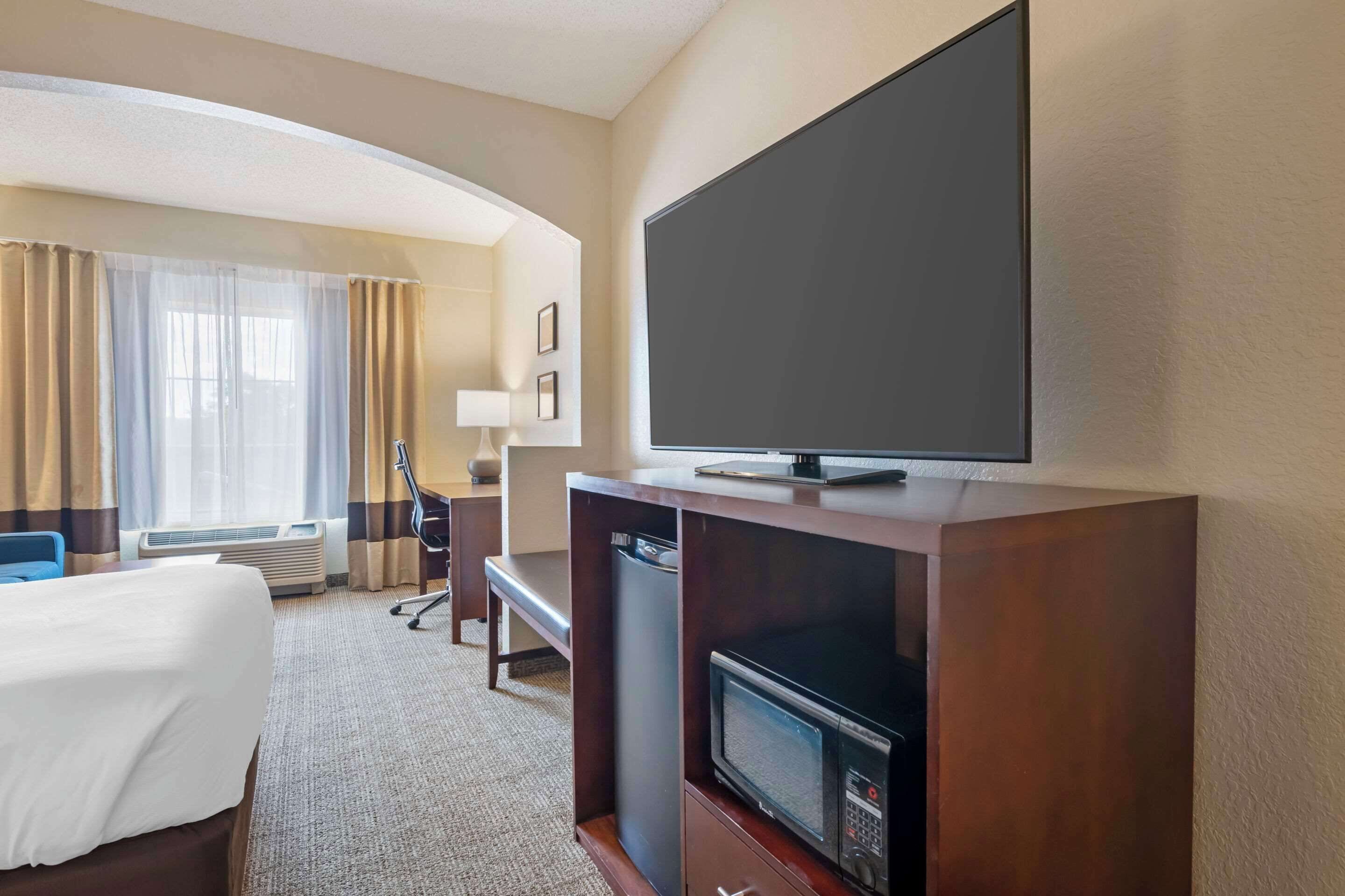 Ein Hotelzimmer mit Bett, Schreibtisch, Fernseher und Mikrowelle.