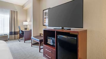 Ein Hotelzimmer mit Bett, Schreibtisch mit Stuhl, Fernseher, Mikrowelle und Kühlschrank.