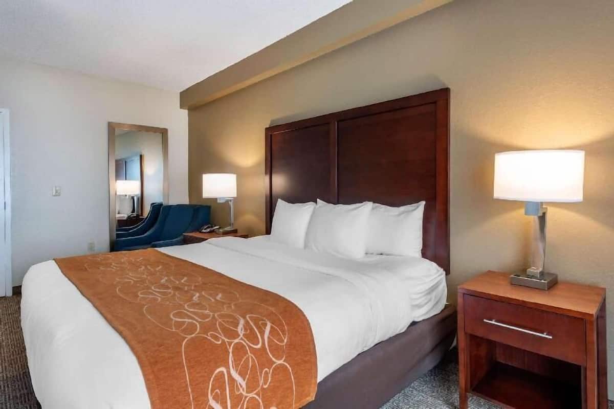 Ett hotellrum med en stor säng, två sängbord, en spegel och en stol.