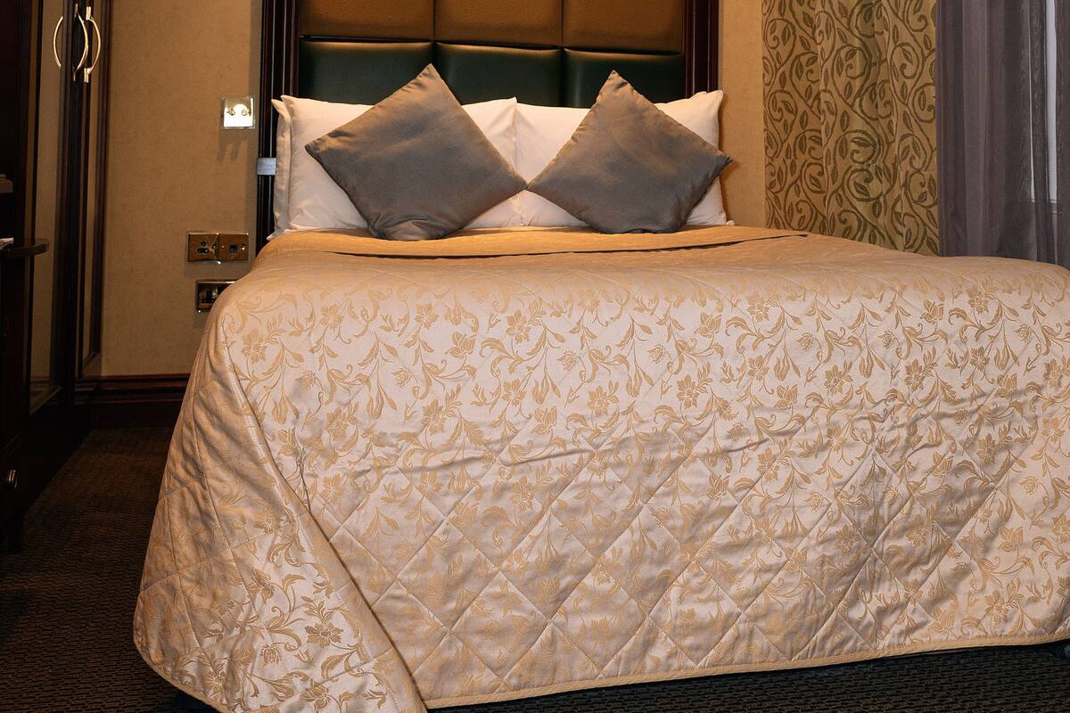 A hotel room with a large bed, a headboard, and a carpeted floor.