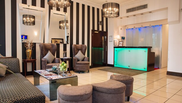 A modern lobby with striped walls, a reception desk, and seating areas. - The Premier Notting Hill (London)