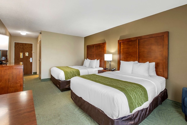A hotel room with two beds, a desk, and a chair.