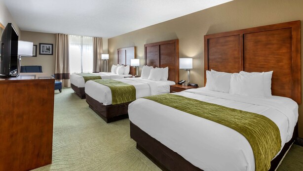 A hotel room with three beds, a desk, and a television. - Comfort Inn Muscatine near Hwy 61 (Muscatine)
