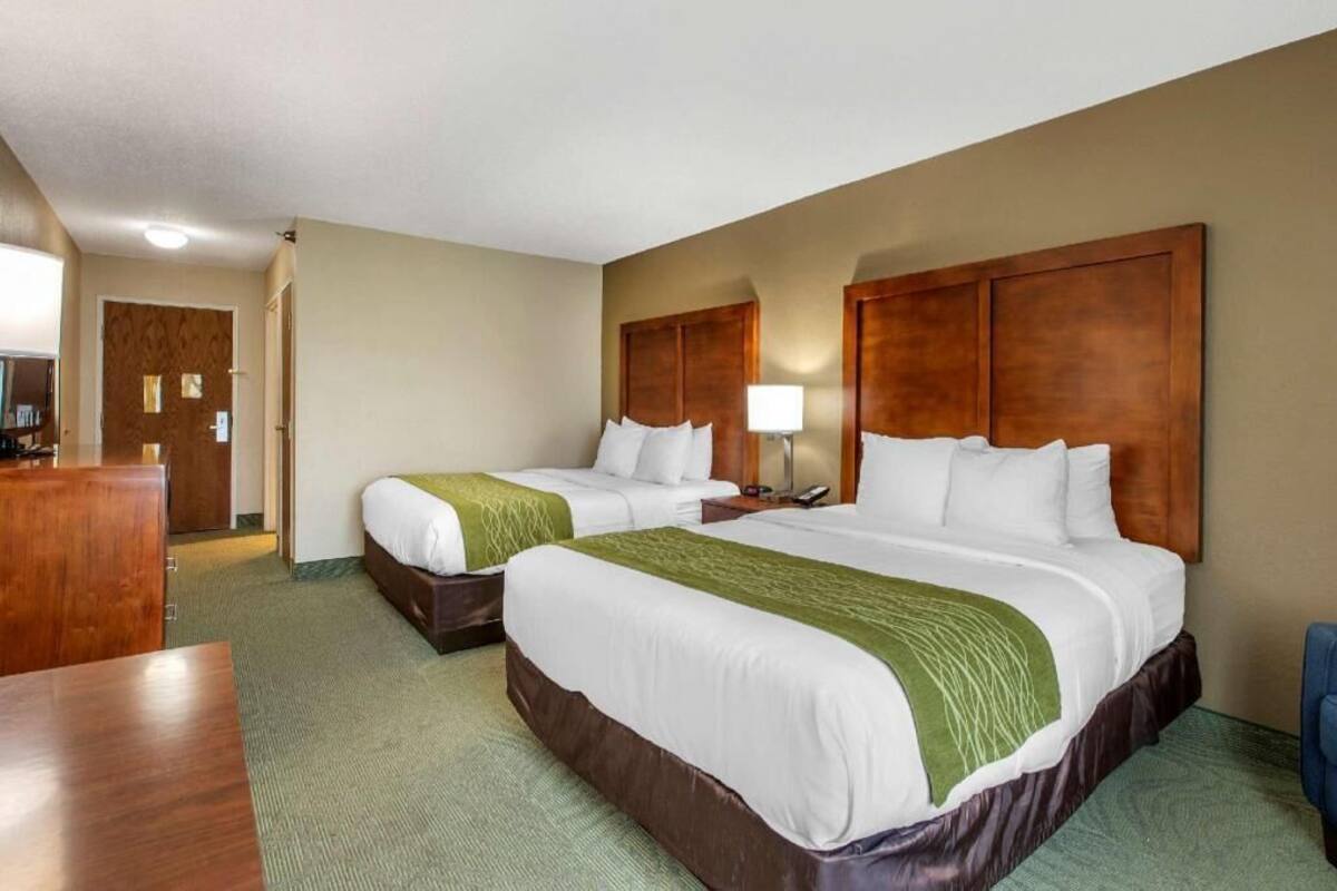 A hotel room with two beds, a desk, and a chair.