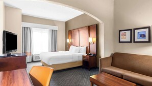 A hotel room with a bed, a desk, a TV, a sofa, and a coffee table.