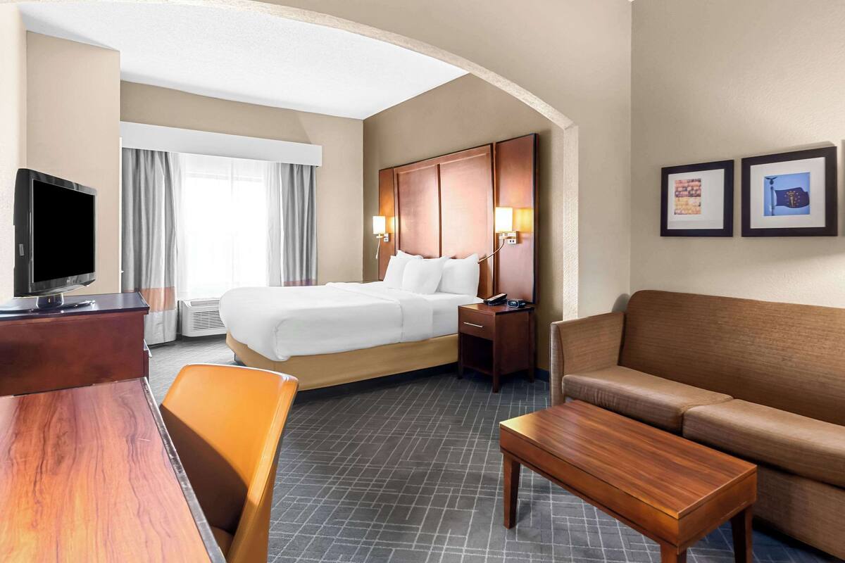 A hotel room with a bed, a desk, a TV, a sofa, and a coffee table.