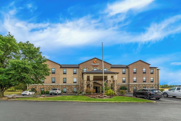 Un hotel Comfort Suites con fachada de piedra, varias ventanas y entrada cubierta.