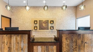A reception area with wooden reception desks, a textured wall, and pendant lighting.