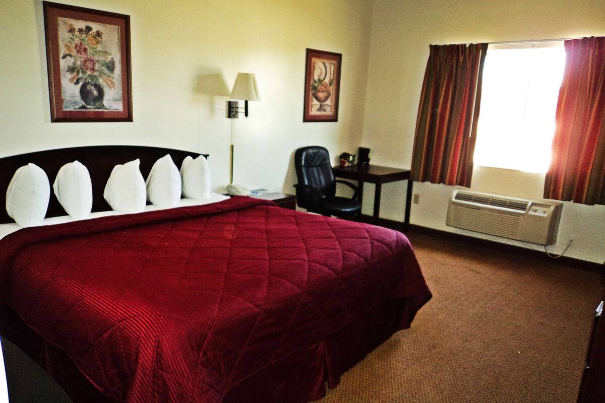 Une chambre d’hôtel équipée d’un grand lit, d’un bureau, d’une chaise, d’une lampe et d’un appareil de climatisation.