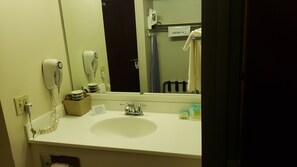 A hotel bathroom with a sink, a hairdryer, a mirror, and a towel rack. - Travelodge by Wyndham Carlsbad NM (Carlsbad)