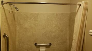 A shower with a grab bar, a handheld showerhead, and a curtain.
