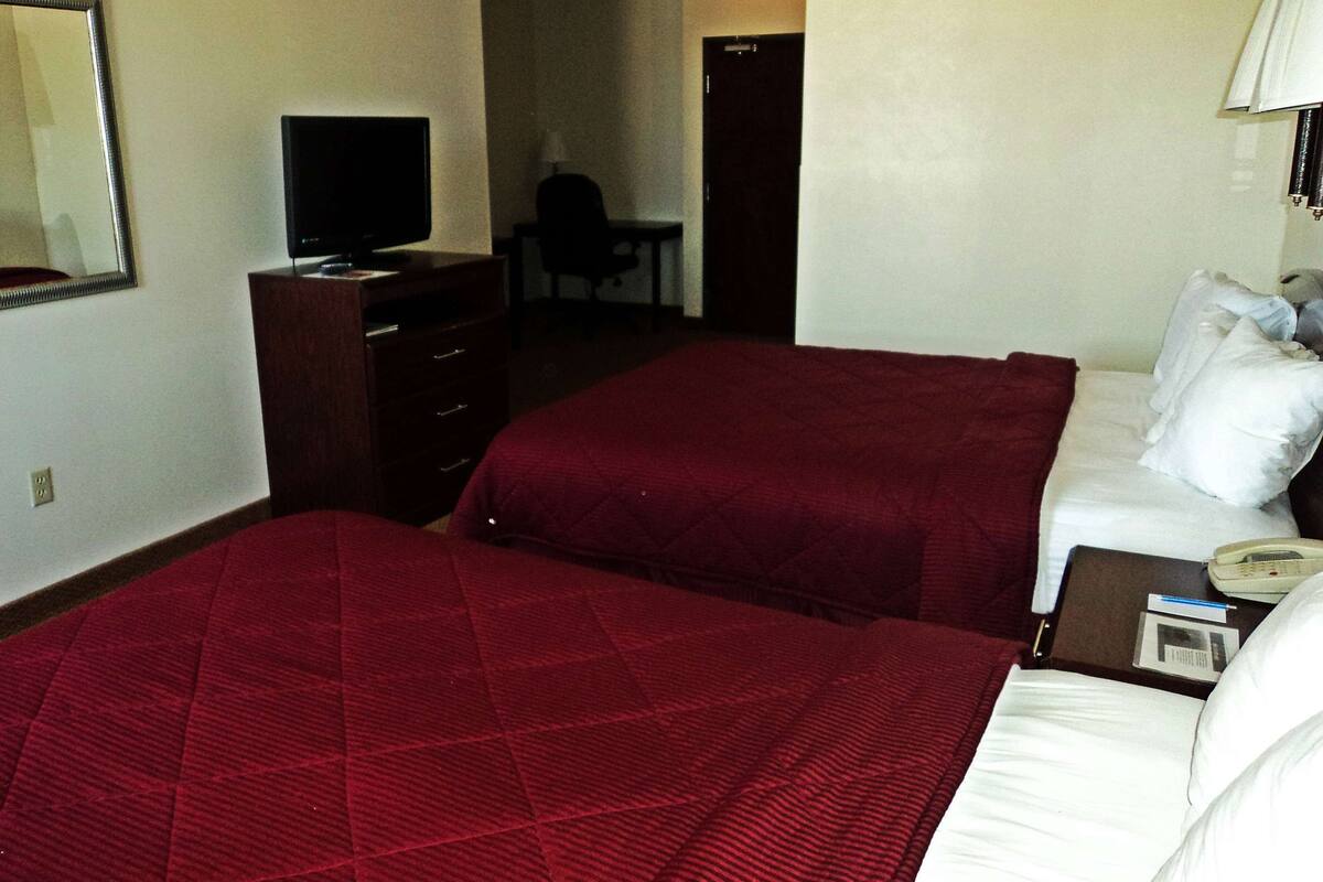 Une chambre d’hôtel avec deux lits, un bureau, une chaise, une télévision et un téléphone.