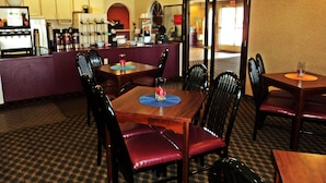 A restaurant with a bar area, multiple tables, and chairs.
