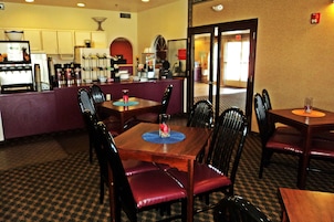 A restaurant with a bar area, multiple tables, and chairs.