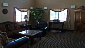 A spacious living room with a large window, a sofa, a coffee table, and a cabinet.