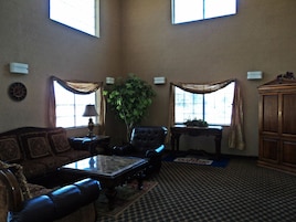 A spacious living room with a large window, a sofa, a coffee table, and a cabinet.