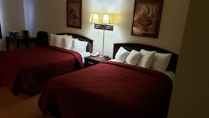 A hotel room with two beds, a desk, a lamp, and a phone.