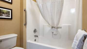 A bathroom with a white bathtub, a toilet, and a shower curtain.