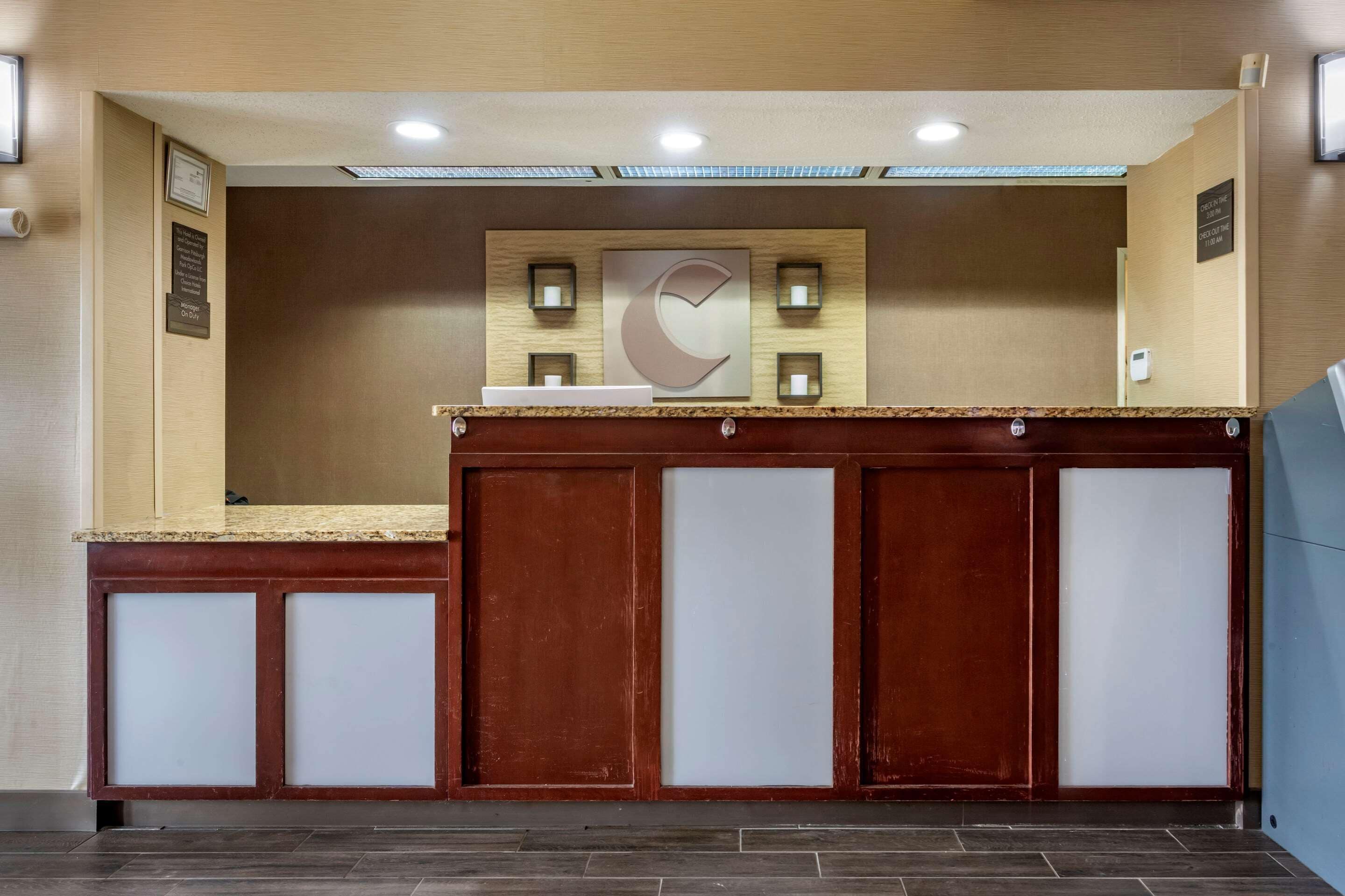A reception desk with a wooden finish and frosted glass panels, a large C-shaped logo on the wall, and a small reception area with a counter.