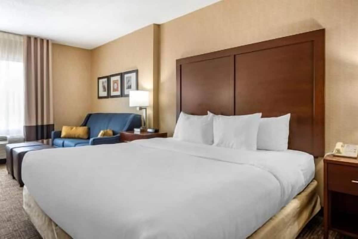 Une chambre d’hôtel avec un grand lit, un bureau, une chaise et une table de chevet.