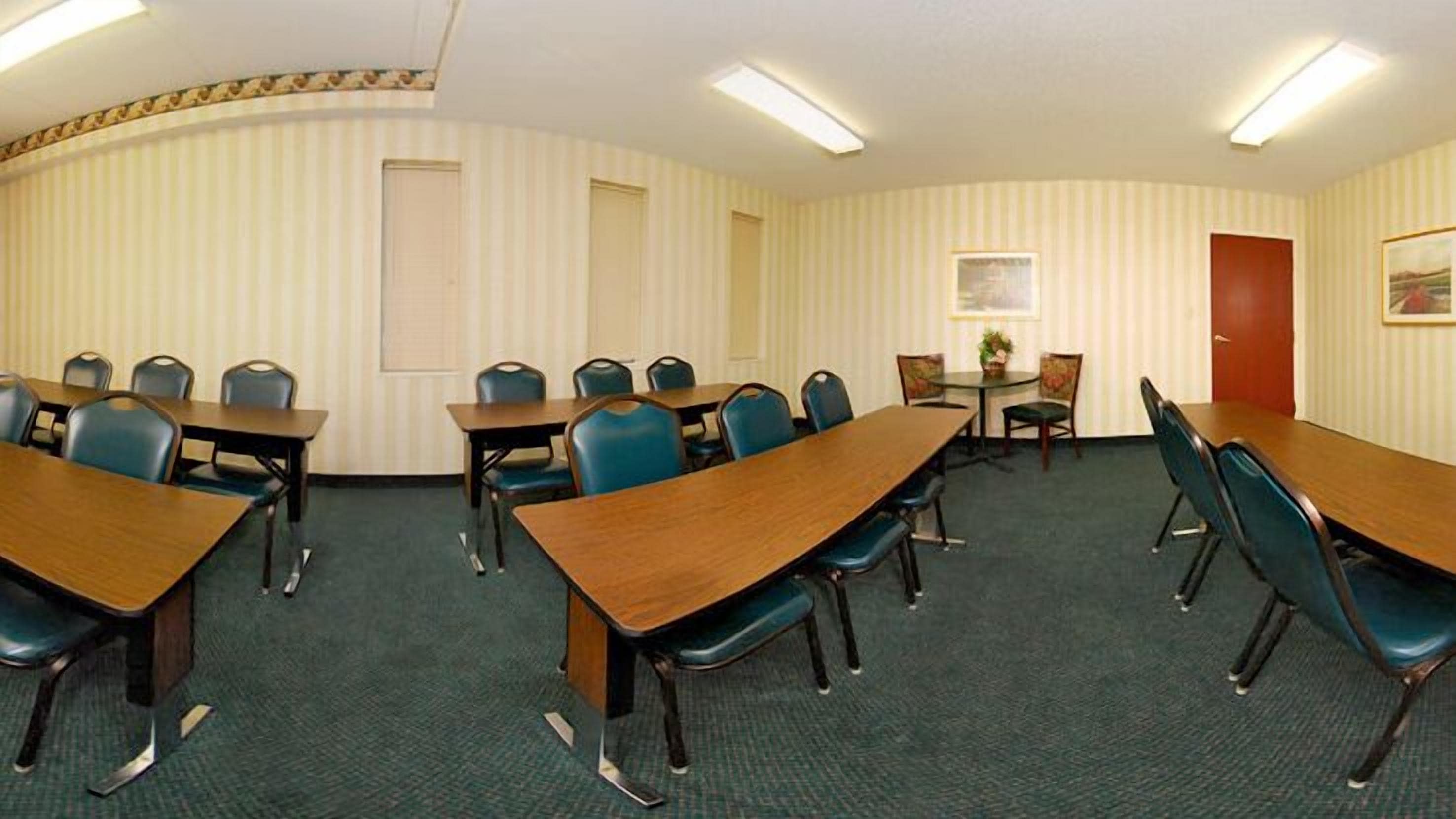 A conference room with a long table, several chairs, and a small table with chairs.
