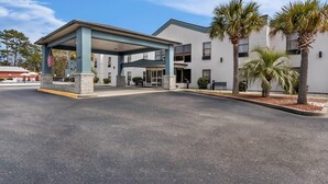 Ein Hotel mit überdachter Einfahrt, Palmen und blauem Himmel.