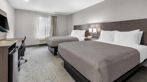 Ein Hotelzimmer mit Bett, Nachttisch, Lampe, Schreibtisch, Stuhl und Fernseher.