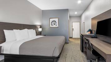 A modern hotel room with a bed, desk, and TV.