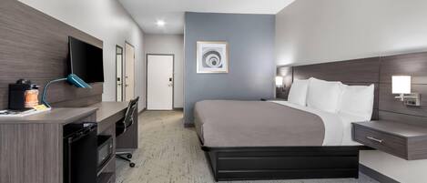 A modern hotel room with a bed, desk, and TV.