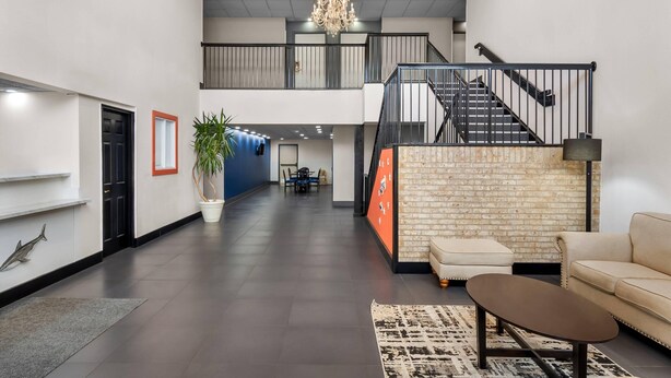 Eine großzügige Lobby mit Treppe, einer Kandelaber und einer Sitzecke mit Couchtisch.