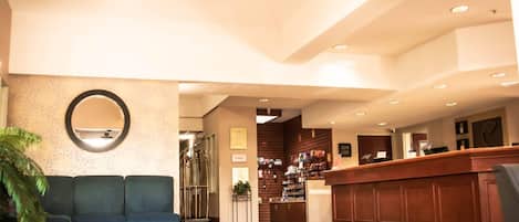 A lobby with a reception desk, a green sofa, and a large mirror.