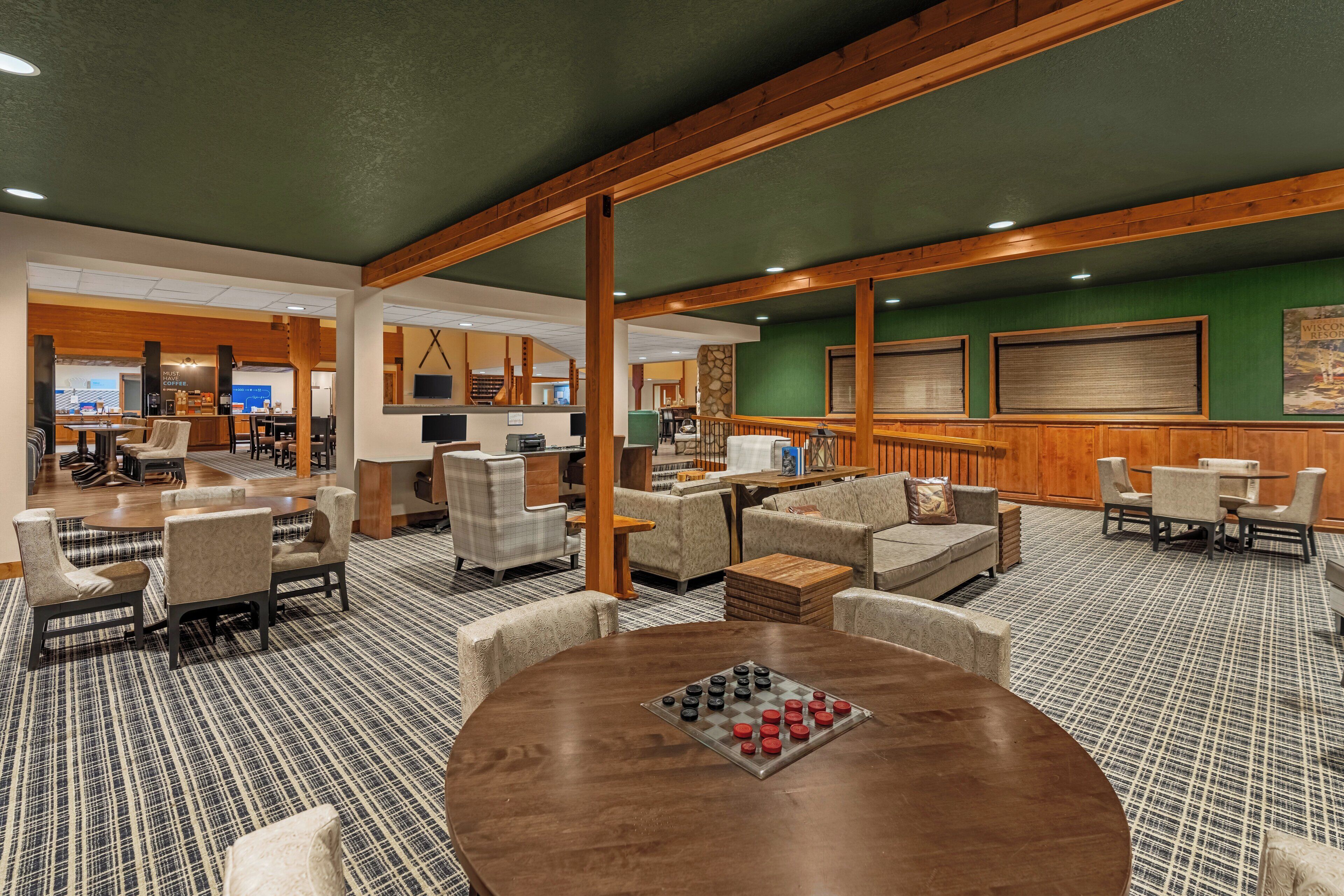 Un hall d’entrée spacieux, doté d’un tapis à carreaux, de poutres en bois et d’espaces salon confortables.