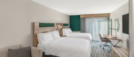 Une chambre d’hôtel avec deux lits, un bureau, une chaise et un téléviseur.